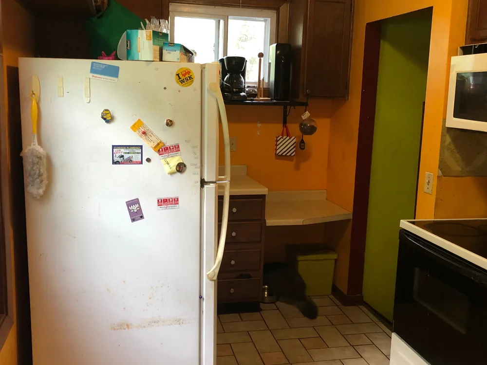 Kitchen before renovation — dated cabinets, worn flooring and original appliances